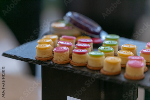 Des petits-fours, encas de conférence sur un plateau en ardoise sont décorés d'un bouton coloré.