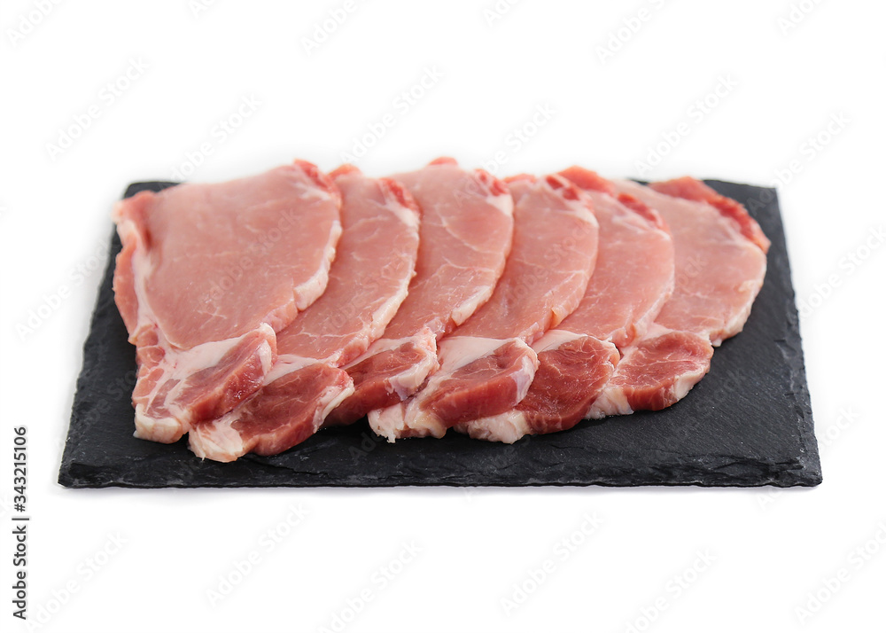 uncooked meat isolated on white. Pieces of pork on black plate uncooked meat isolated on white. Pieces of pork on black plate