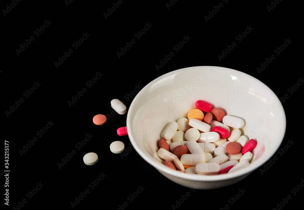 Different medicine pills, tablets in a white saucer on black background. Many different pills. Health care. Top view. Space for text. Copy space. New image. Closeup. Pharmaceutical picture Different medicine pills, tablets in a white saucer on black background. Many different pills. Health care. Top view. Space for text. Copy space. New image. Closeup. Pharmaceutical picture