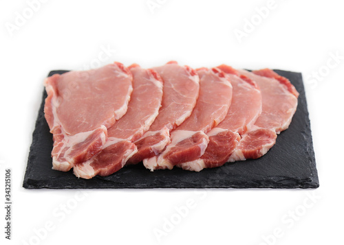 uncooked meat isolated on white. Pieces of pork on black plate