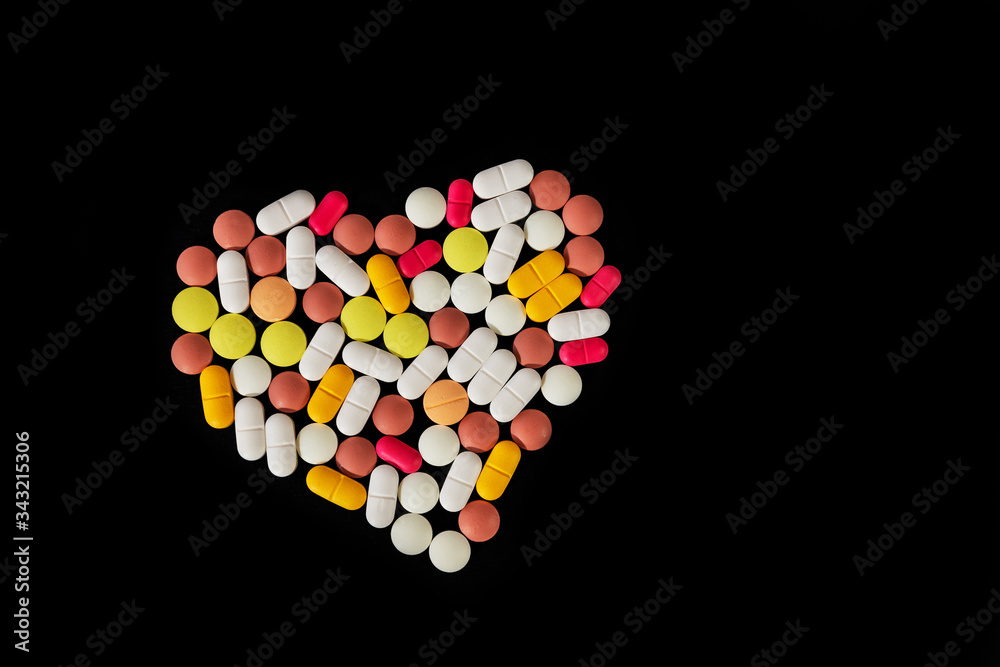 Many different pills and tablets folded in shape of heart on black background. Many pills and tablets with space for text. Health care. Top view. Copy space. New image. Pharmaceutical picture Many different pills and tablets folded in shape of heart on black background. Many pills and tablets with space for text. Health care. Top view. Copy space. New image. Pharmaceutical picture