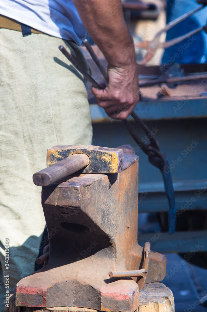blacksmith performs the forging of hot glowing metal on the anvil blacksmith performs the forging of hot glowing metal on the anvil