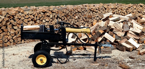 Wood splitter with heap and piled wood behind