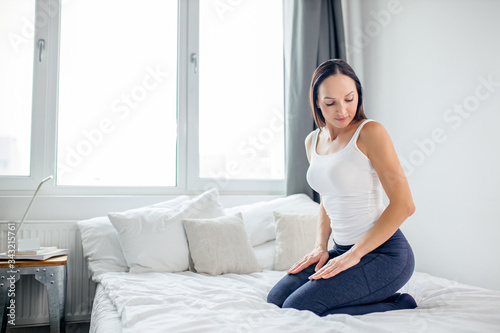side view on calm woman sitting on bed after yoga exercises in the morning, happy woman feel freedom in her mind and body