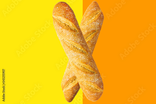 фотографія Freshly baked artisan whole french baguettes with golden crusty floury texture on duotone yellow orange background