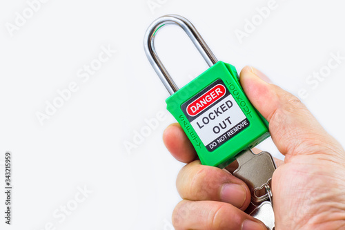 Hand holding green key lock and tag for process cut off electrical,the toggle tags number for electrical log out tag out on white background