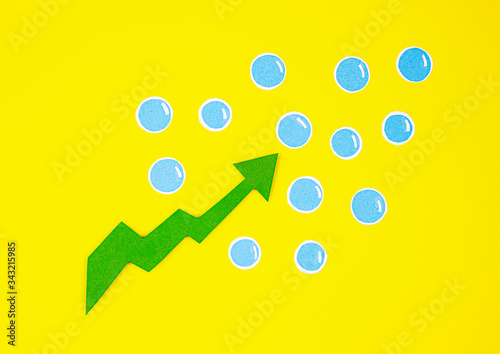 the paper green arrow is pointing upwards with blue bubbles on a yellow background. the concept of increase, growth, success, increase of something