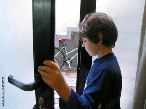 A young boy looks under the door waiting to go outside to play. Stay at home. Protection for the covis-19, Coronavirus pandemic. 