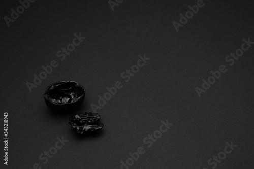 Black walnut shell on a matte black background. Copy space. Dark mode