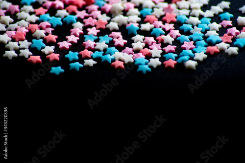 multicolored confectionery sprinkle in the form of stars on a black background