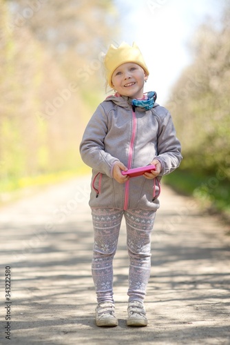 Little girl in the park holding a smartphone in his hand, child's portrait.