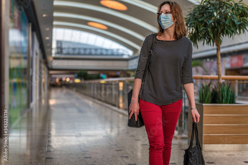 Junge Frau mit Atemschutzmaske läuft durch ein leeres Einkaufszentrum