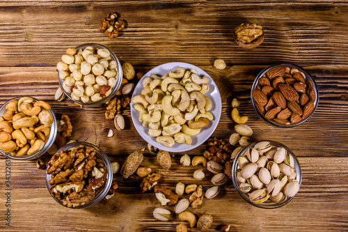 Various nuts (almond, cashew, hazelnut, pistachio, walnut) in bowls on a wooden table. Vegetarian meal. Healthy eating concept. Top view