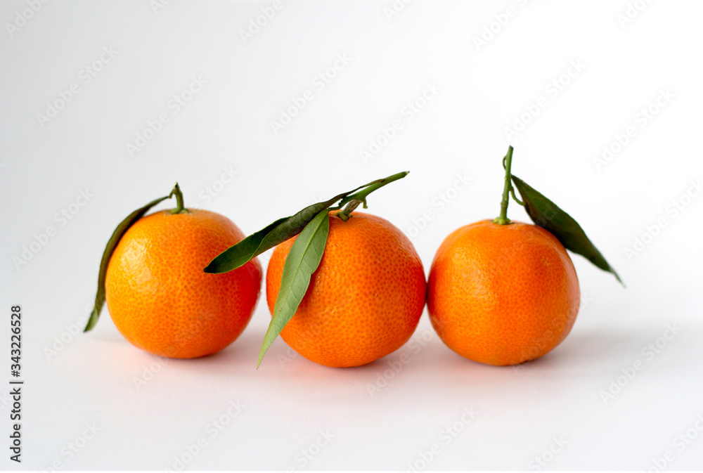 Three tangerines with green leaves on a white background. Three tangerines with green leaves on a white background.