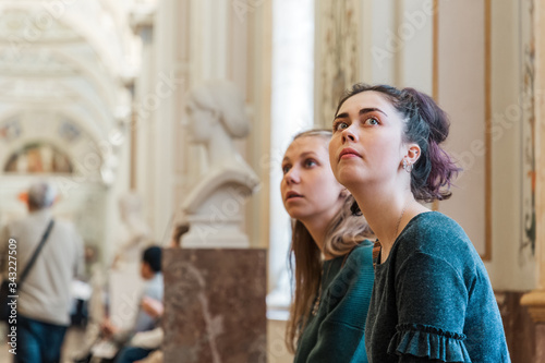 Obraz na plátně Two young Caucasian women look at the Museum's exhibits with surprise