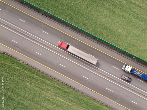 Dump trucks carrying goods on the highway. Red truck driving on asphalt road along the green fields. seen from the air. Aerial view landscape. drone photography. cargo delivery