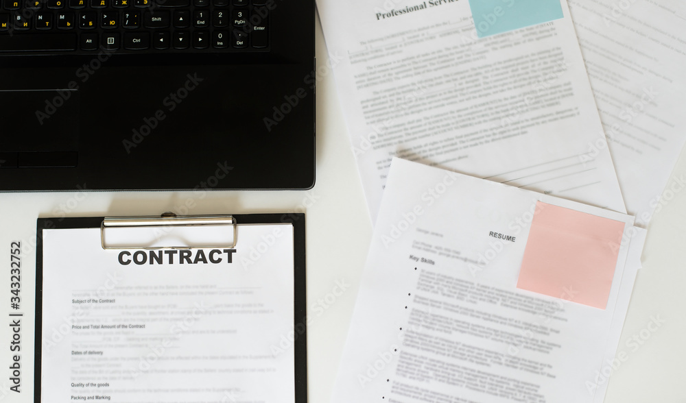 Obraz premium Top view of contract in clipboard lying at office on table with laptop and documents