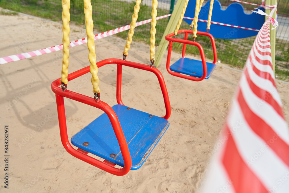 Swing for children and Tape barrier in a closed playground during the period of quarantine and pandemic covid-19, Coronavirus.