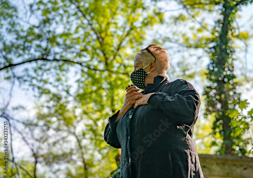 Senior woman in black dotted mask in a cemetery