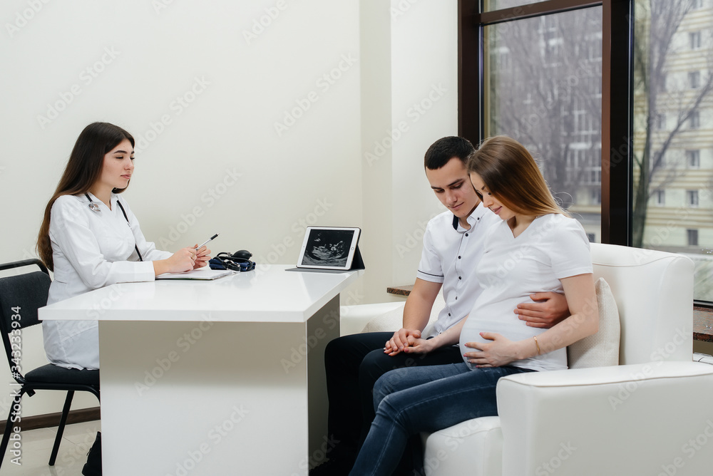 A young couple waiting for a baby to consult a gynecologist after an ultrasound. Pregnancy, and health care A young couple waiting for a baby to consult a gynecologist after an ultrasound. Pregnancy, and health care