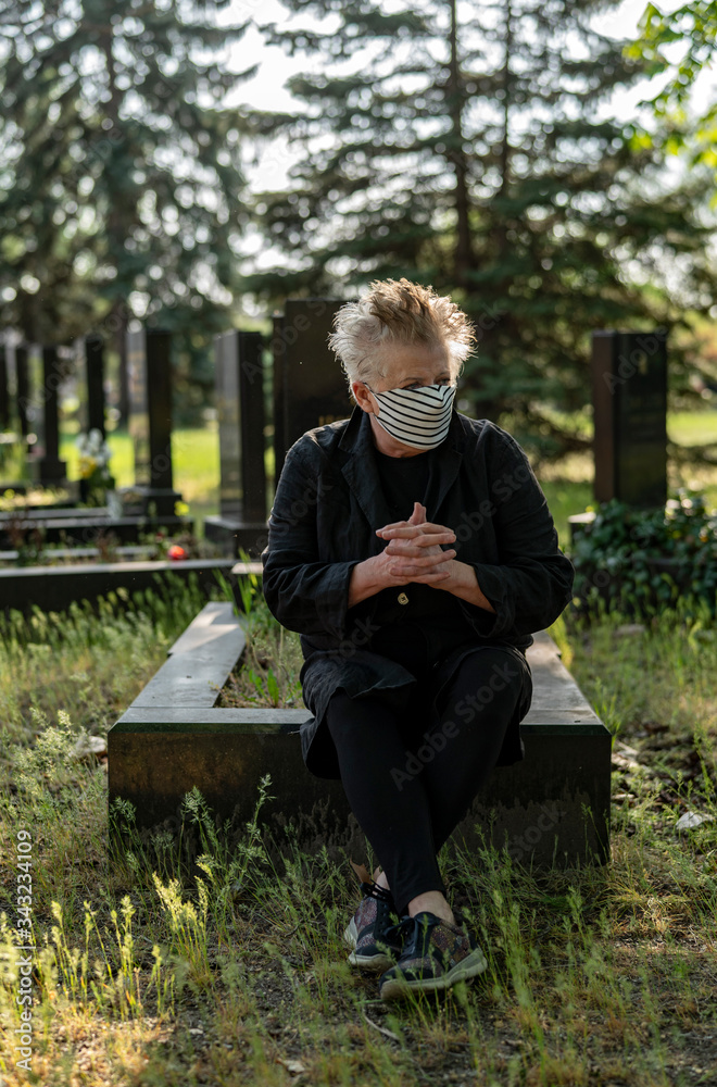 Senior woman in black dotted mask in a cemetery