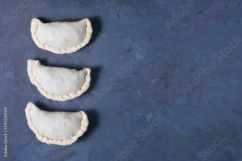 three raw empanadas. A traditional Argentinian dish