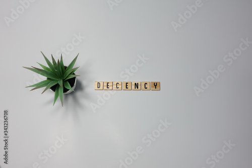 The word Decency written in wooden letter tiles on a white background.