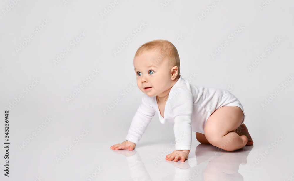 Chubby ginger baby boy in bodysuit, barefoot. He smiling, creeping on floor isolated on white background. Close up, copy space Chubby ginger baby boy in bodysuit, barefoot. He smiling, creeping on floor isolated on white background. Close up, copy space