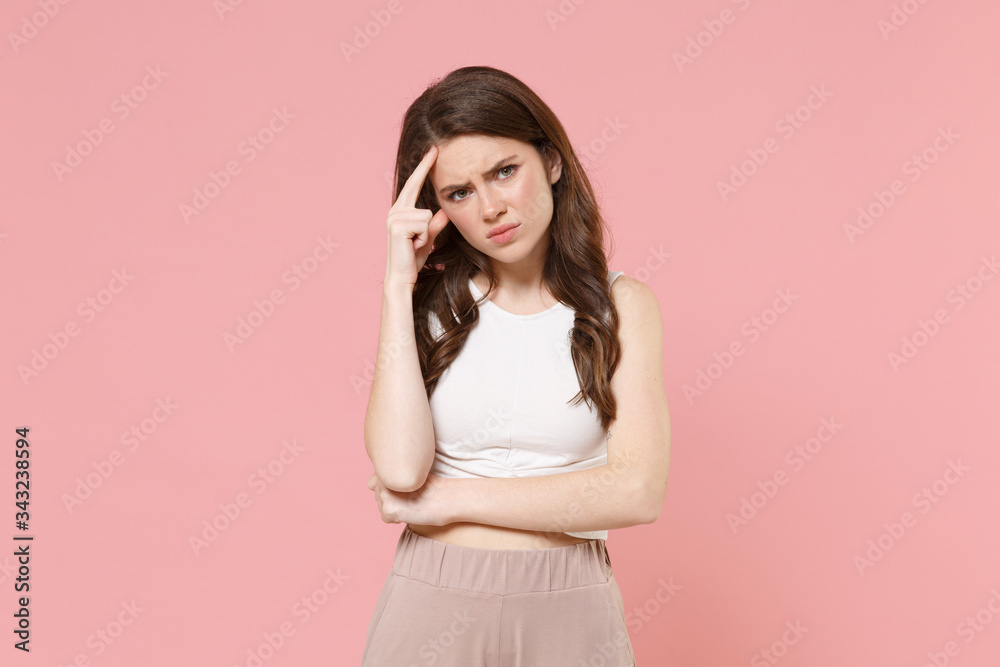 Preoccupied tired young brunette woman girl in light casual clothes posing isolated on pastel pink wall background studio portrait. People lifestyle concept. Mock up copy space. Put hand on head.