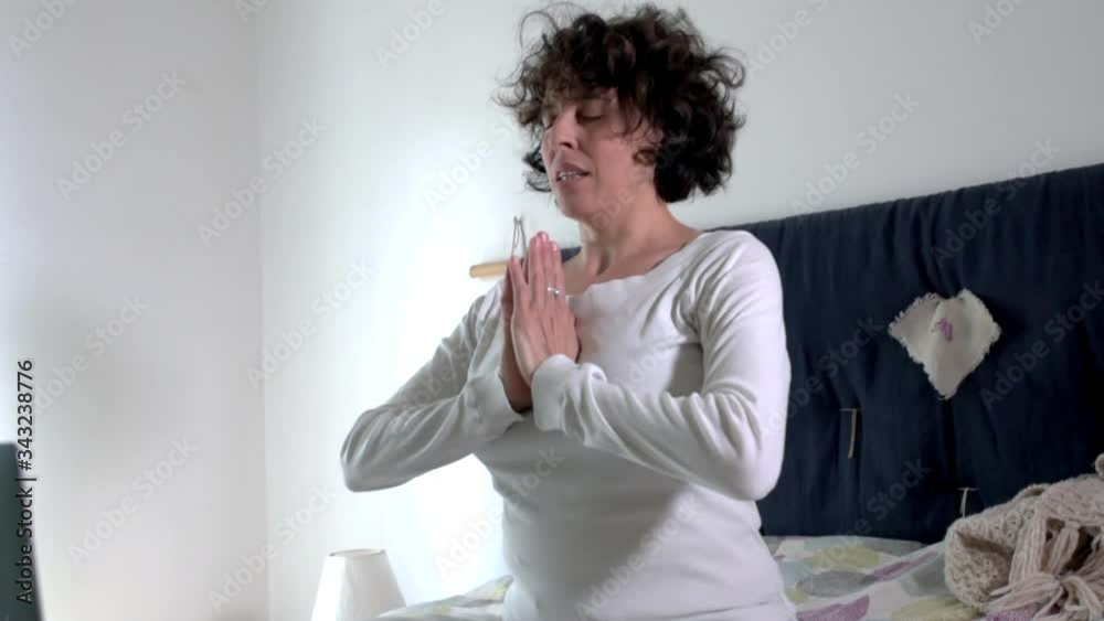 woman apprentice of meditation and yoga performs the ritual rewards by holding hands gathered in the mudra of pray, lotus pose, quarantine time practice in front of the computer woman apprentice of meditation and yoga performs the ritual rewards by holding hands gathered in the mudra of pray, lotus pose, quarantine time practice in front of the computer