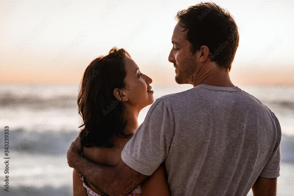 Loving young couple watching a sunset over the ocean Loving young couple watching a sunset over the ocean
