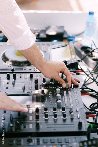 DJ plays music on the beach. Dj mixing beach party in summer vacation outdoor. Disc jockey hands playing music for tourist people. Hand of a deejay playing music on professional mixing controller