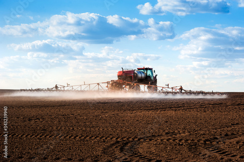 self-propelled red sprayer with long arms disperses fertilizers on agricultur...