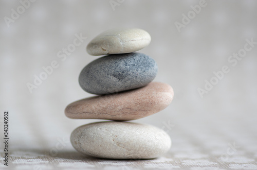 Stone cairn on striped grey white background, four stones tower, simple poise stones, simplicity harmony and balance,