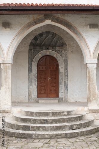Entrance to an old Muslim building in oriental style, through an arch with columns, steps, carved doors. in front of cable tiles