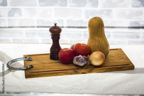 still life of fresh vegetables tomatoes garlic pumpkin onion cutting board spoons and blade