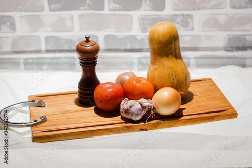 still life of fresh vegetables tomatoes garlic pumpkin onion cutting board spoons and blade