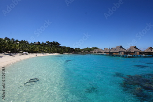 A paradise beach with white sand, turquoise water, coco palms and over-water bungalows for a relax travel holidays.