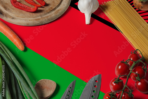 Malawi flag on fresh vegetables and knife concept wooden table. Cooking concept with preparing background theme.