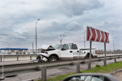 Wrecked car pickup truck crash accident on highway city road. Damaged big white vehicle after collision accident waiting for police and towing truck