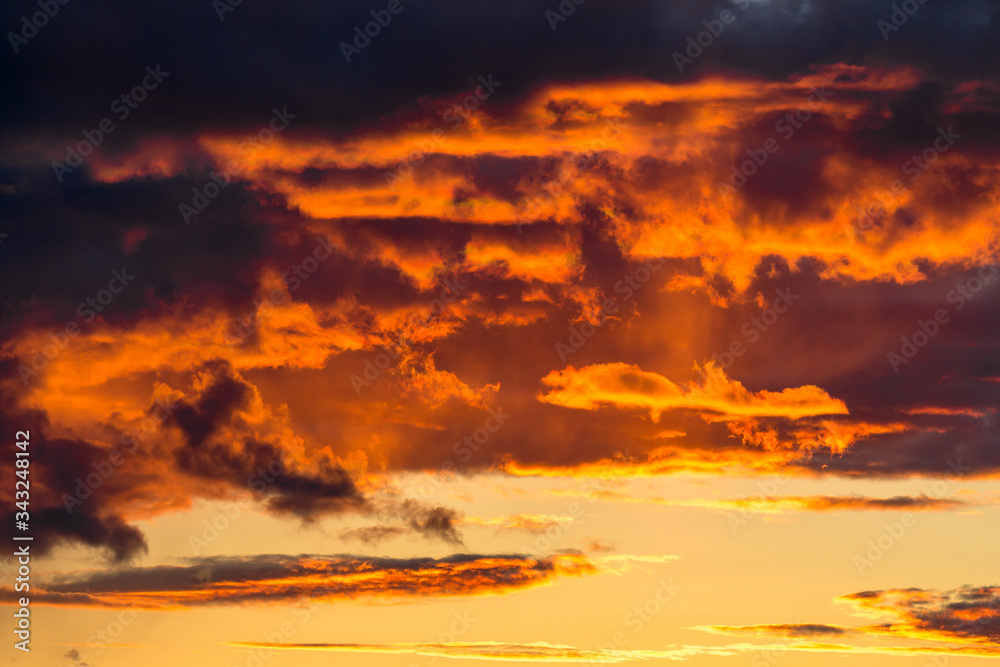 Clouds illuminated at sunset by fiery yellow sunlight
