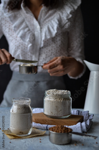 Woman Chef Measuring Flour on Background with Different Flours on Display