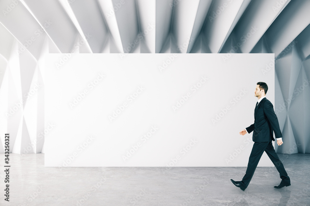 Businessman walking in modern gallery interior Businessman walking in modern gallery interior
