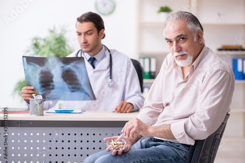 фотографія Young male doctor and old patient in antismoking concept