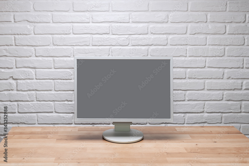 Blank screen computer monitor on working desk with brick wall Blank screen computer monitor on working desk with brick wall