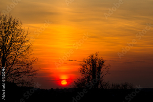 The bright red sun sets over the horizon. Red yellow sunset 
