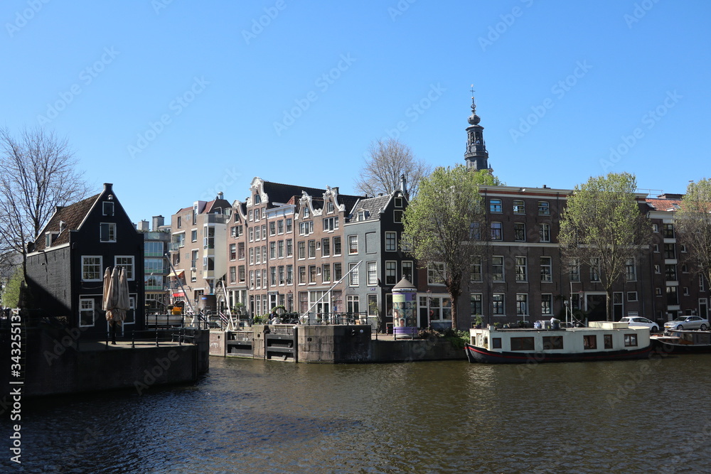 sunny view of buildings over water canal in Amsterdam