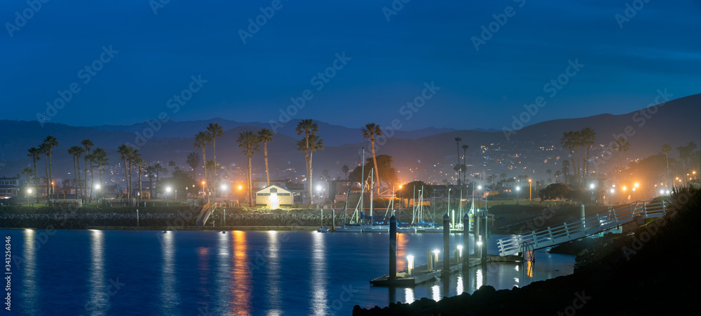 Panoramic view of lamps reflected in the harbor cove water before sun rises on the Southern California neighborhood.