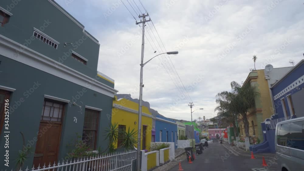 A peaceful POV walking down a street with colorfully painted buildings and palm trees and looking up at a pigeon on a telephone wire - Cape Town, South Africa A peaceful POV walking down a street with colorfully painted buildings and palm trees and looking up at a pigeon on a telephone wire - Cape Town, South Africa