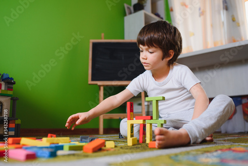 Foto child little boy playing with wooden cubes toys in nursery at home or daycare ce